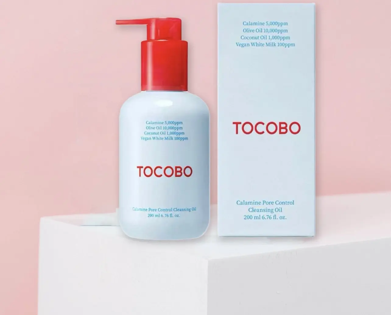 Aceite limpiador facial Tocobo Calamine Pore Control de 200 ml, con envase blanco y dispensador rojo, junto a su caja sobre una base blanca y fondo rosa.