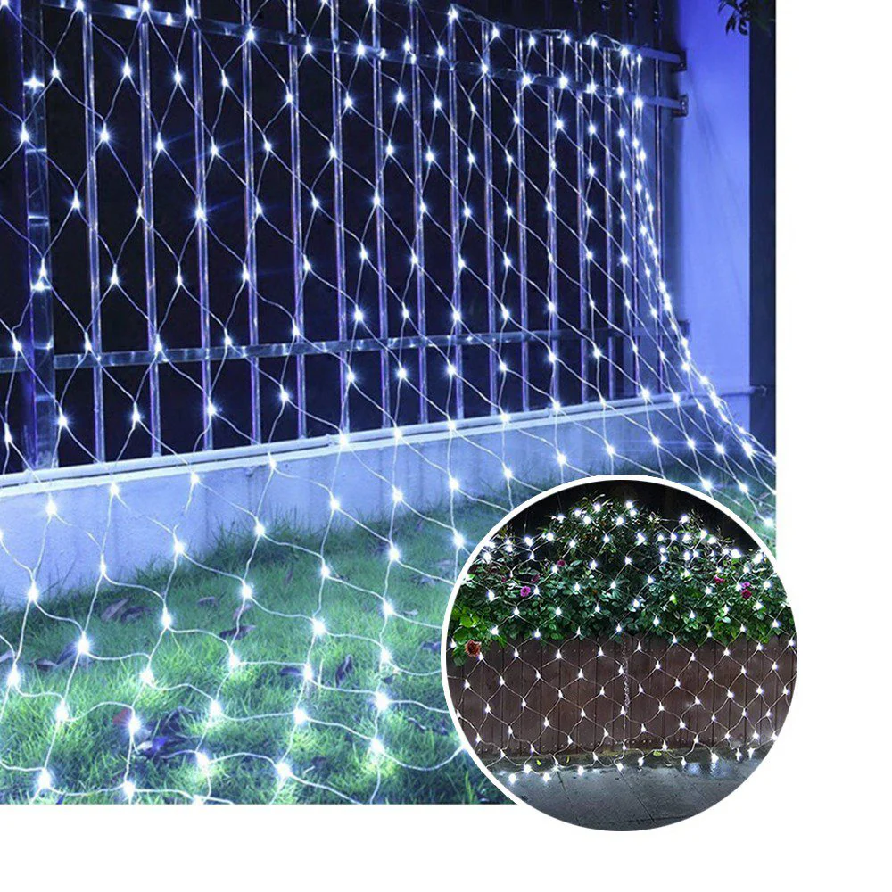 Red de luces LED blancas en forma de malla sobre reja metálica y césped, iluminando un jardín oscuro.