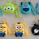 Set x7 llaveros monederos de silicona en colores azul, verde, amarillo y negro con personajes animados y correa estampada.