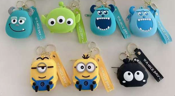Set x7 llaveros monederos de silicona en colores azul, verde, amarillo y negro con personajes animados y correa estampada.