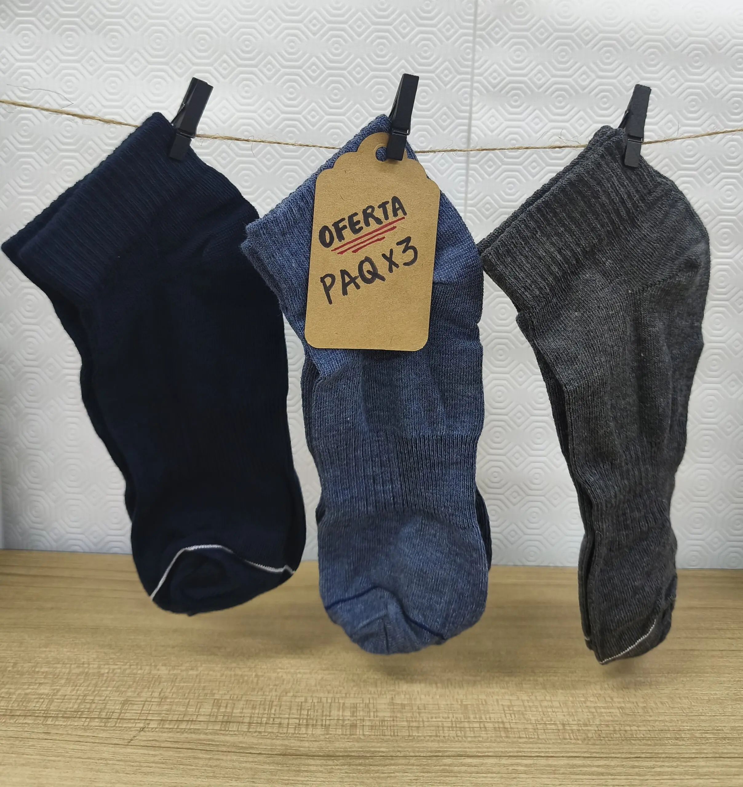 Pack de tres medias tobilleras de algodón en azul marino, azul y gris, colgadas de un cordel con etiqueta de oferta de tres unidades.
