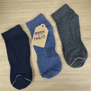 Pack de tres medias tobilleras en colores azul oscuro, jaspeado y gris sobre superficie de madera con etiqueta de oferta.