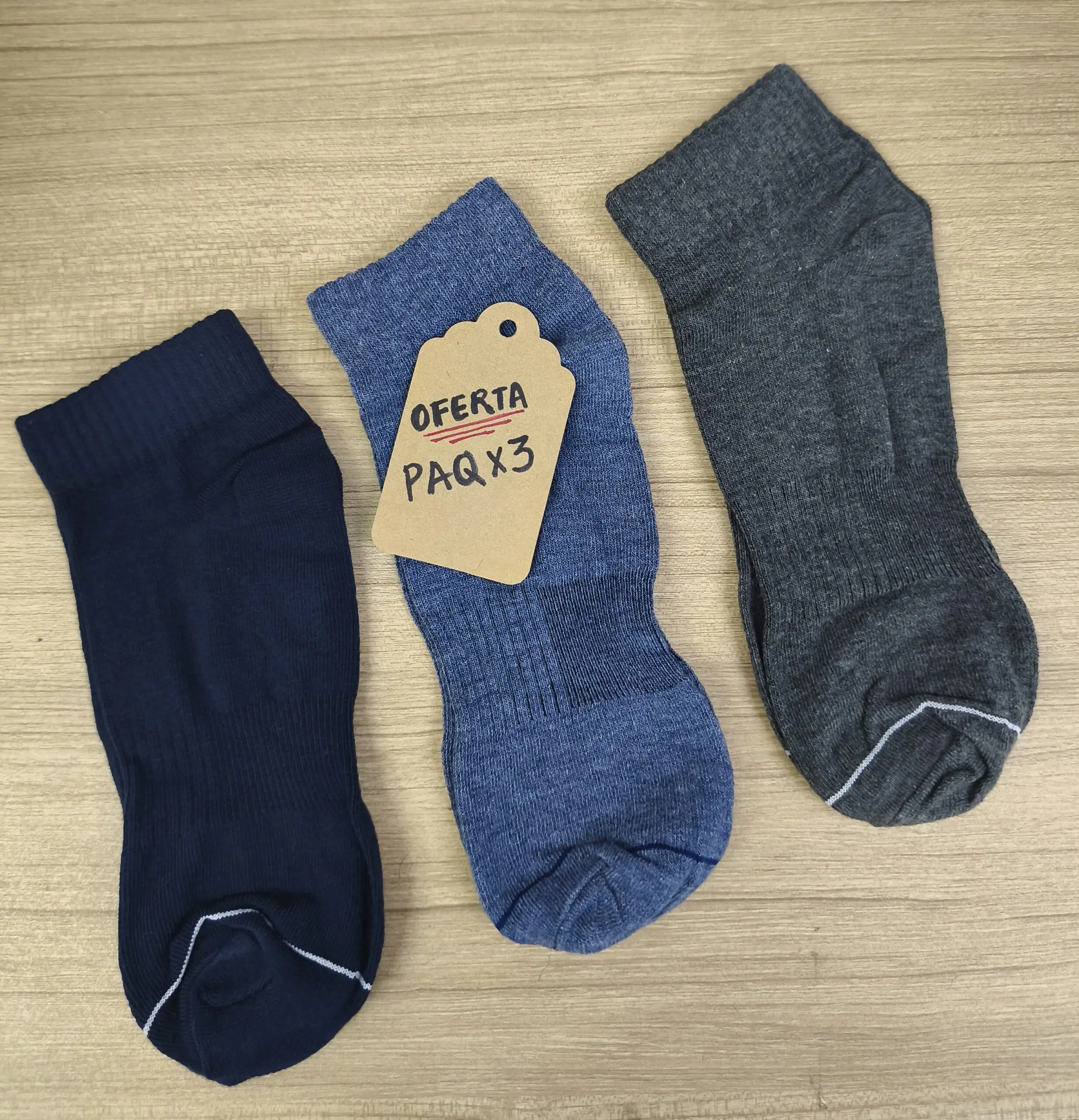 Pack de tres medias tobilleras en colores azul oscuro, jaspeado y gris sobre superficie de madera con etiqueta de oferta.