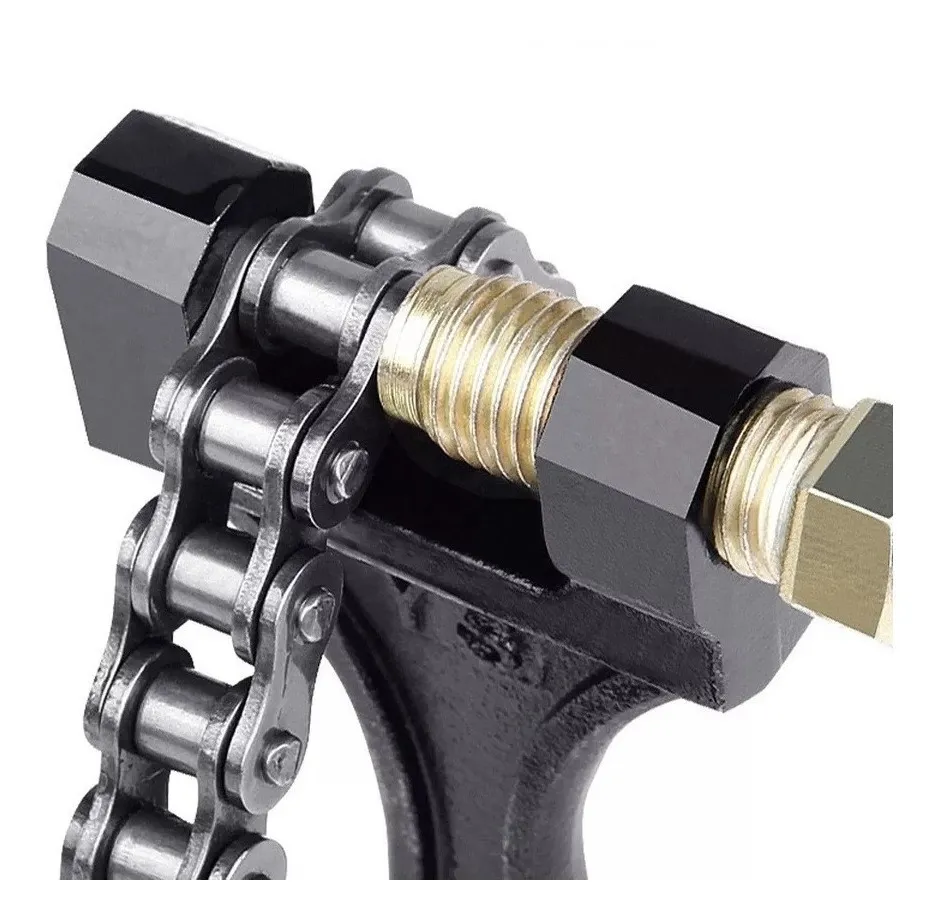 Primer plano de despinador de cadena para moto con tornillo de bronce y piezas negras, ajustando una cadena metálica de rodillos.