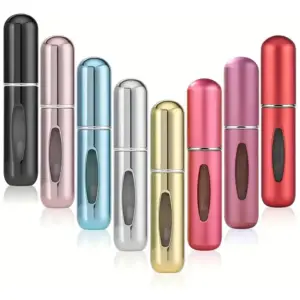 Ocho dispensadores de perfume recargables de 5 ml en colores variados, dispuestos en forma de V, con ventana transparente y acabado metálico brillante.