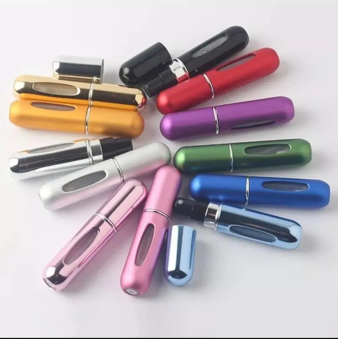 Conjunto de dispensadores de perfume recargables de 5ml en diversos colores metálicos, dispuestos en abanico sobre fondo blanco con tapas y atomizadores.