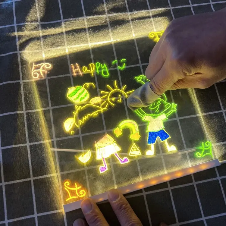 Tablero led de acrílico transparente con dibujos brillantes, siendo borrado con un paño por una mano sobre una superficie de cuadrícula oscura.