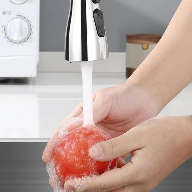Grifo lavaplatos retráctil de acero inoxidable con control de flujo, lavando un tomate rojo bajo el chorro de agua.