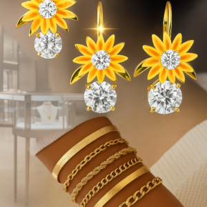 Pendientes dorados con flores amarillas y cristales junto a cinco pulseras doradas de diversas texturas en una muñeca.