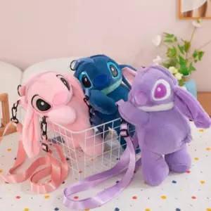 Tres bolsos bandolera de peluche con diseño de Stitch y Angel en colores rosa, azul y morado, con correa ajustable dentro de una canasta blanca.