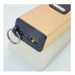 Dispositivo de defensa personal dorado con linterna, puerto Micro USB, interruptor y argolla metálica tipo llavero para transporte urbano.