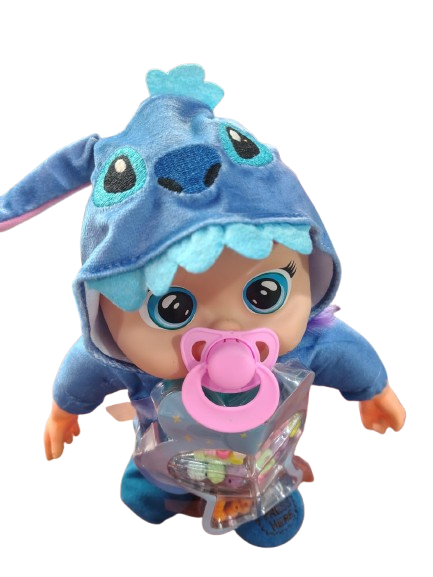 Muñeco bebé con disfraz de animal azul de peluche, ojos grandes, chupete rosa y envase transparente con accesorios de colores.
