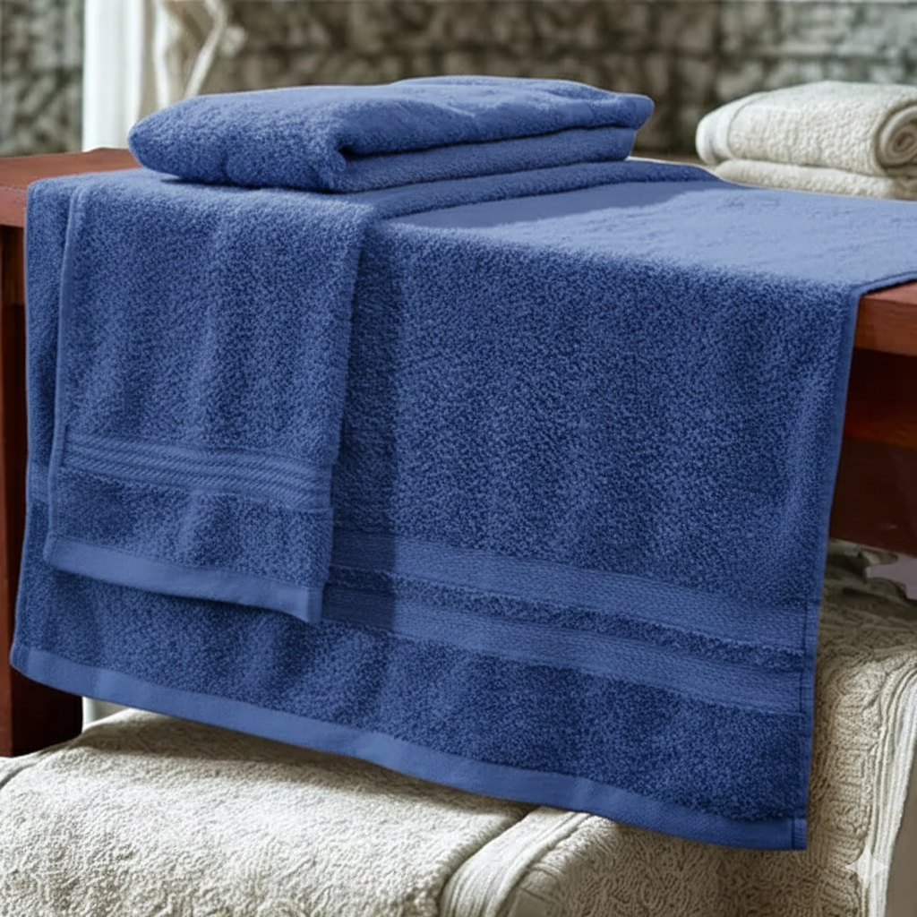 Set de dos toallas hoteleras azules de algodón texturizado con franjas decorativas, dobladas y dispuestas sobre una mesa de madera.