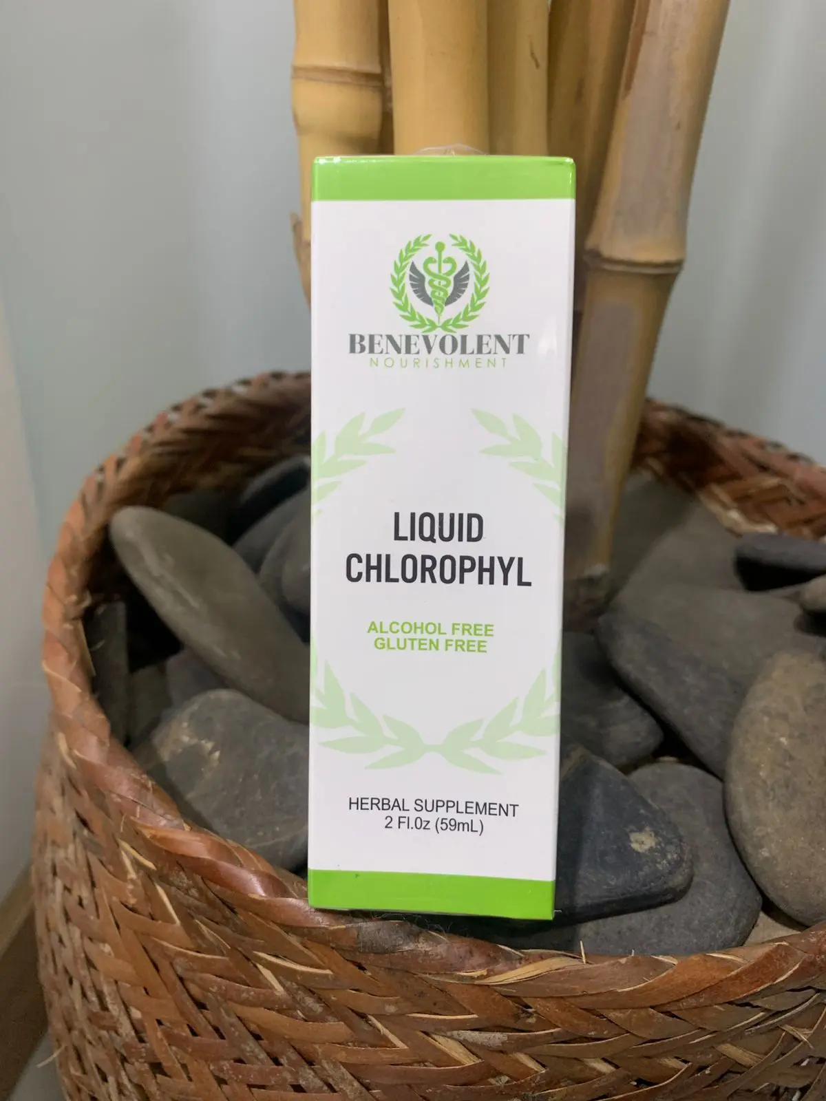 Caja de suplemento de clorofila líquida Benevolent Nourishment de 2 fl oz, envase blanco con detalles verdes sobre piedras grises.