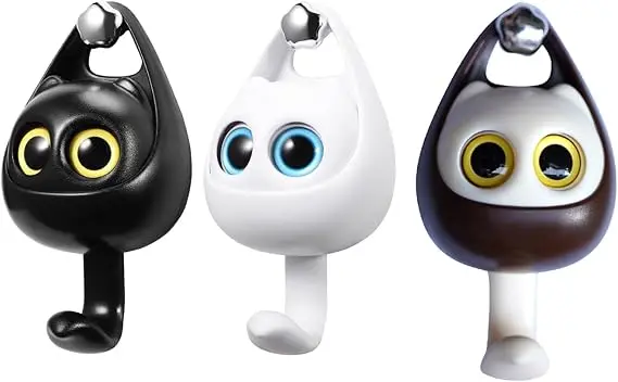 Tres ganchos porta llaves de pared con diseño de gato interactivo y ojos móviles, en colores negro, blanco y marrón con detalles plateados.