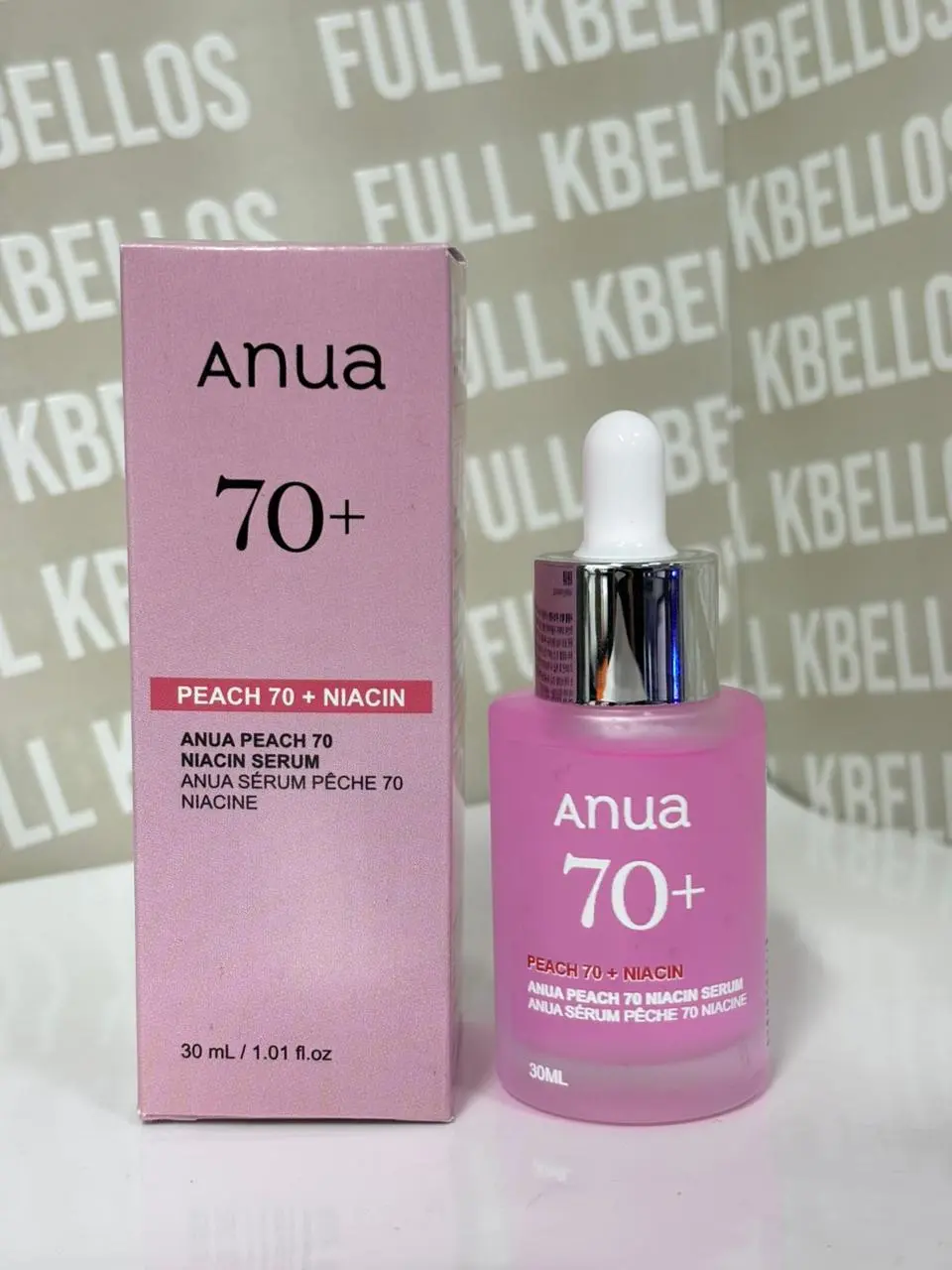 Sérum facial iluminador rosado Anua Peach 70 con niacinamida en botella de vidrio de 30 ml junto a su caja de cartón a juego.