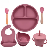 Set de vajilla infantil en silicona color rosa viejo: incluye plato dividido con succión, tazón, babero ajustable, vaso con pitillo y cubiertos con mango.