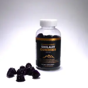 Frasco transparente de gomitas de shilajit con etiqueta negra y dorada, acompañado de varias gomitas moradas oscuras en forma de montaña sobre superficie blanca.