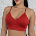 Top deportivo rojo de soporte medio con escote en V, tirantes delgados y banda elástica ancha, usado por modelo en plano frontal.