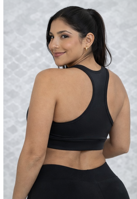 Top deportivo negro de espalda tipo nadadora y ajuste firme, mostrado desde un ángulo lateral posterior en una mujer de talla plus.