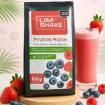 Empaque de 100g de batido en polvo sabor frutos rojos sobre base de madera, acompañado de vaso con batido, fresas y arándanos frescos.