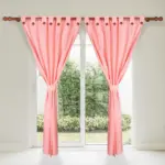 Set de dos cortinas jacquard color salmón con presillas decorativas, colgadas en barra de madera sobre puerta corrediza con vista al jardín.