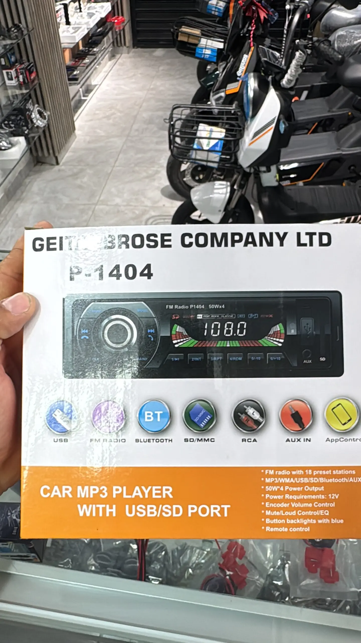 Empaque de radio 1 Din Geitin Brose modelo P-1404 con Bluetooth, USB y SD. Caja blanca y naranja que muestra el equipo con pantalla y controles.