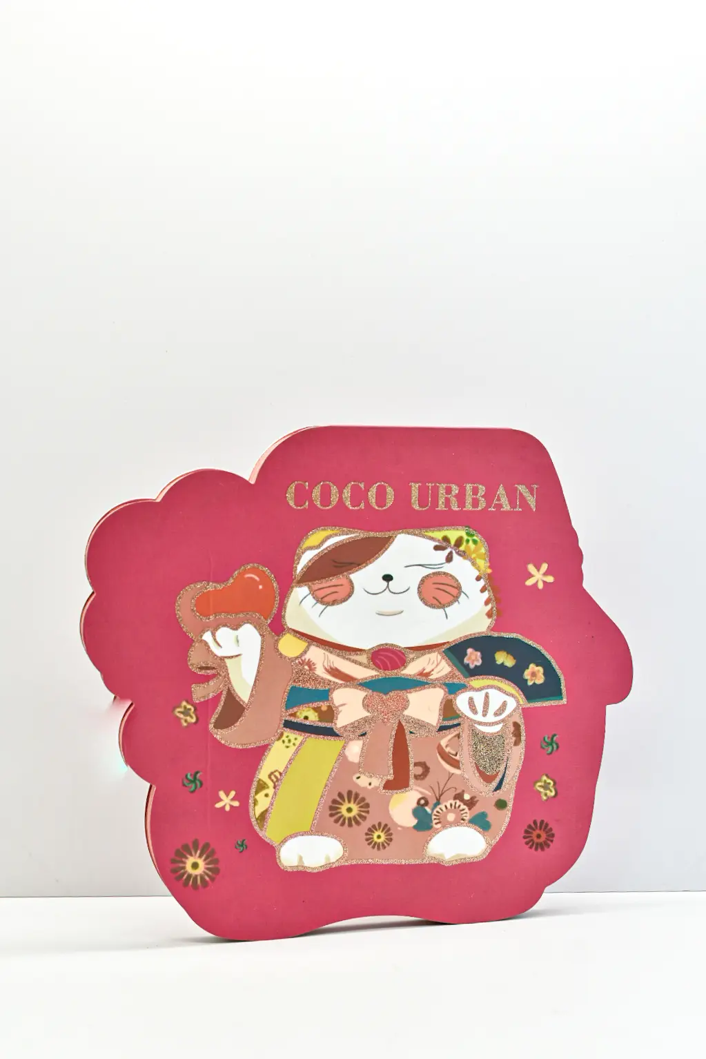Paleta de sombras de ojos rosada con forma de gato de Coco Urban, adornada con detalles dorados y diseño tradicional japonés.