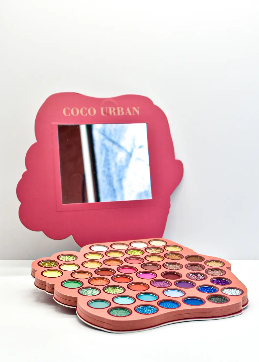 Paleta de sombras Coco Urban rosa en forma de gato con espejo integrado y múltiples tonos coloridos en acabados mate y glitter.