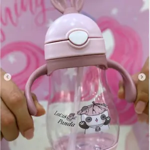 Termo infantil rosa con asas, orejas de conejo, pitillo y de panda Lotus Panda sobre fondo decorado