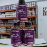 Tres frascos morados de suplemento para cabello Rainbow Nutrients en pirámide, sobre fondo de estantería comercial.