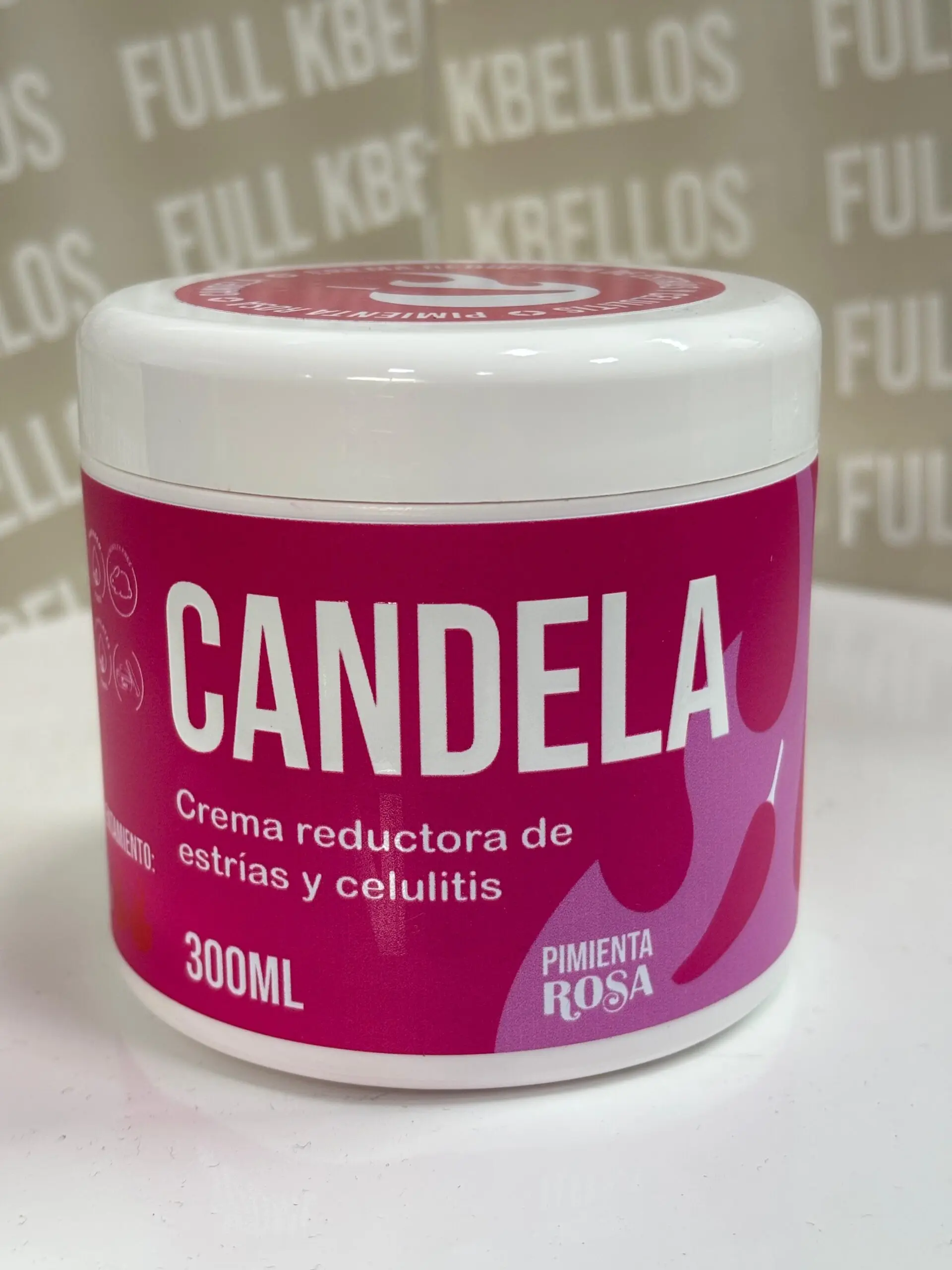 Tarro blanco de 300 ml con etiqueta fucsia, texto blanco de crema reductora para estrías y celulitis con pimienta rosa, sobre superficie blanca.
