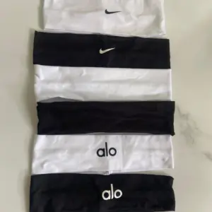 Seis balacas deportivas de algodón en blanco y negro con logos de Nike y Alo, dispuestas verticalmente sobre una superficie clara.
