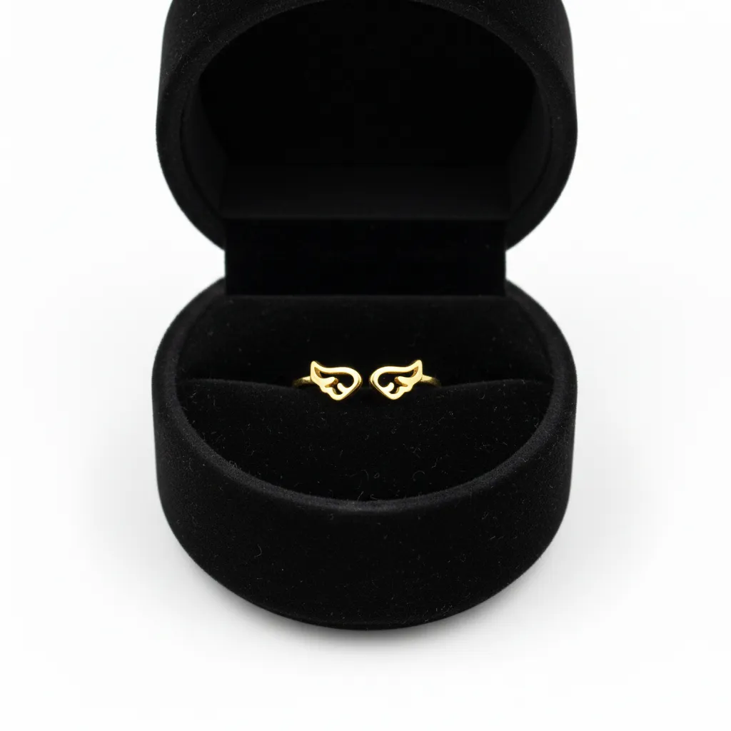 Anillo dorado con diseño de alas minimalistas dentro de un estuche circular de terciopelo negro.