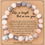 Pulsera artesanal de piedra natural en tonos blancos y grises con dije plateado en forma de corazón y tarjeta con mensaje motivacional.