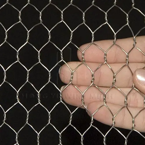 Malla metálica hexagonal galvanizada plateada con tejido de alambre entorchado, mostrada en primer plano sobre mano humana.