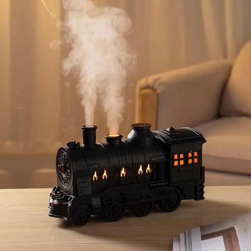 Humidificador de aire negro diseño tren a vapor sobre mesa de madera con luces LED cálidas simulando fuego y vapor saliendo de la chimenea.