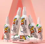 Seis envases de spray Depilya con diseños de ondas coloridas, dispuestos en grupo sobre un fondo rosado con sombras geométricas.