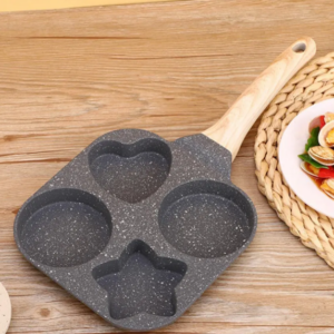 Sartén 4 en 1 antiadherente de granito gris con mango de madera y cavidades de corazón, estrella y dos círculos sobre mesa de madera.