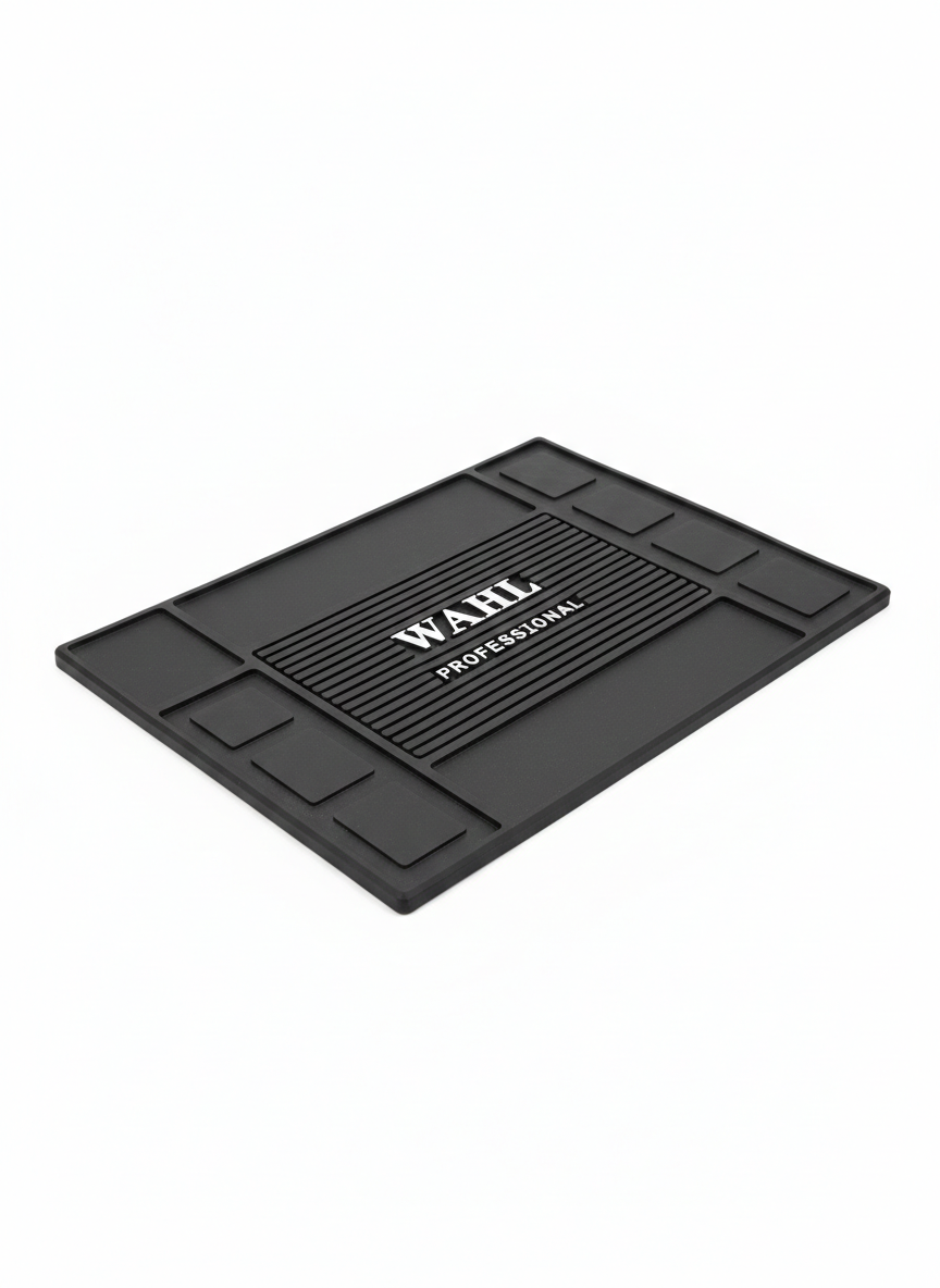 Tapete negro Wahl Professional con textura estriada central y compartimentos rectangulares para organizar herramientas de barbería.