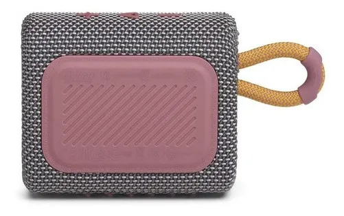 Parlante Bluetooth portátil gris texturizado con placa de goma rosa y correa naranja para colgar.