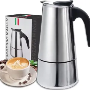 Cafetera italiana de acero inoxidable para 6 tazas junto a su caja, una taza de café con arte latte y granos de café sobre una superficie blanca.