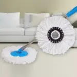 Trapero giratorio con cabezal de microfibra blanca y mango metálico ajustable, mostrando el repuesto circular con centro negro frente a un sofá blanco.