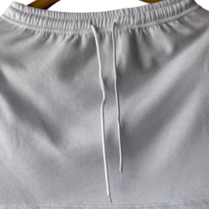 Falda casual blanca de algodón perchado tipo cargo, con pretina elástica, cordón ajustable y bolsillos laterales con solapa.