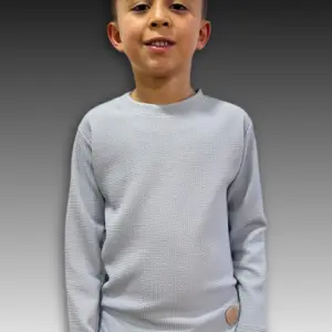 Buzo infantil gris claro de tela texturizada galleta, manga larga, corte urbano con parche en el dobladillo y cuello redondo.