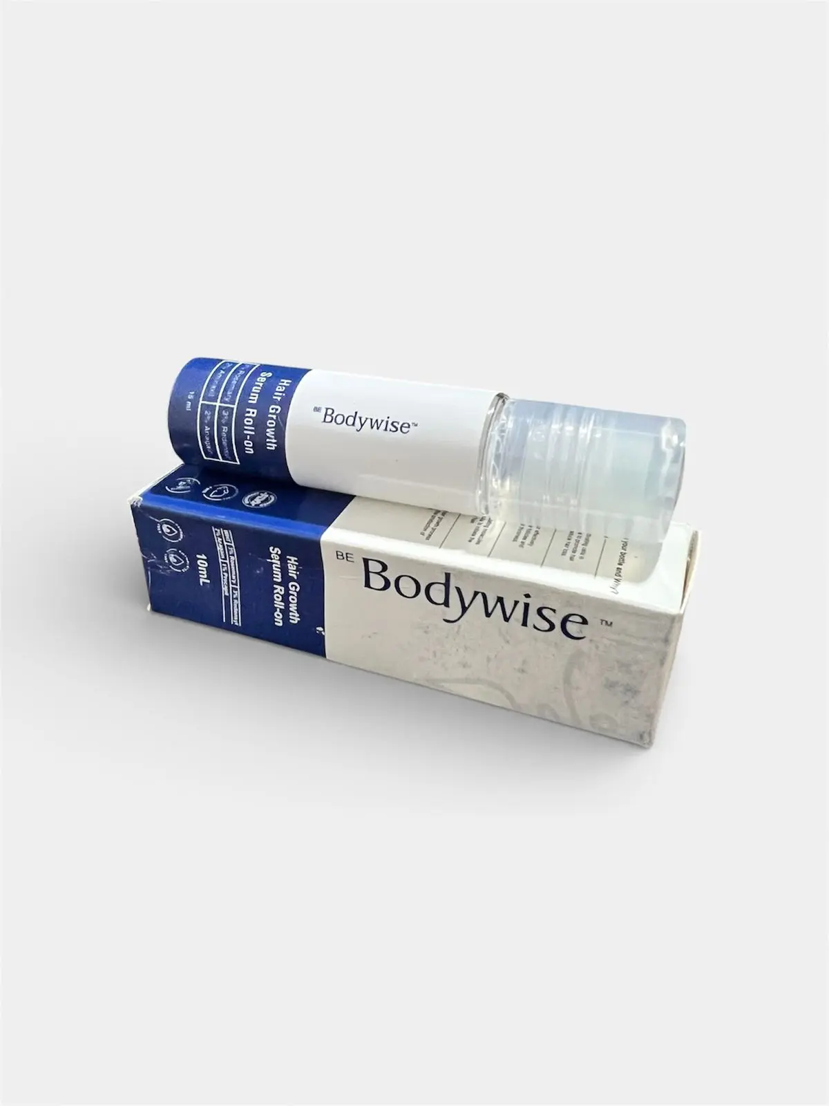 Aplicador roll-on blanco y azul de Bodywise sobre su caja blanca, tratamiento capilar anticaída.