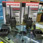 Dos radios portátiles Baofeng BF-888S negros con antenas, sobre cajas de empaque, acompañados de bases de carga, manos libres y clips.