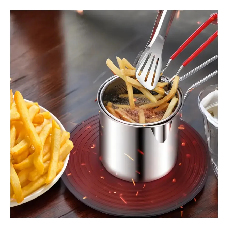 Olla freidora individual de acero inoxidable con cesta coladora sobre base roja, mientras pinzas metálicas retiran papas fritas crujientes.