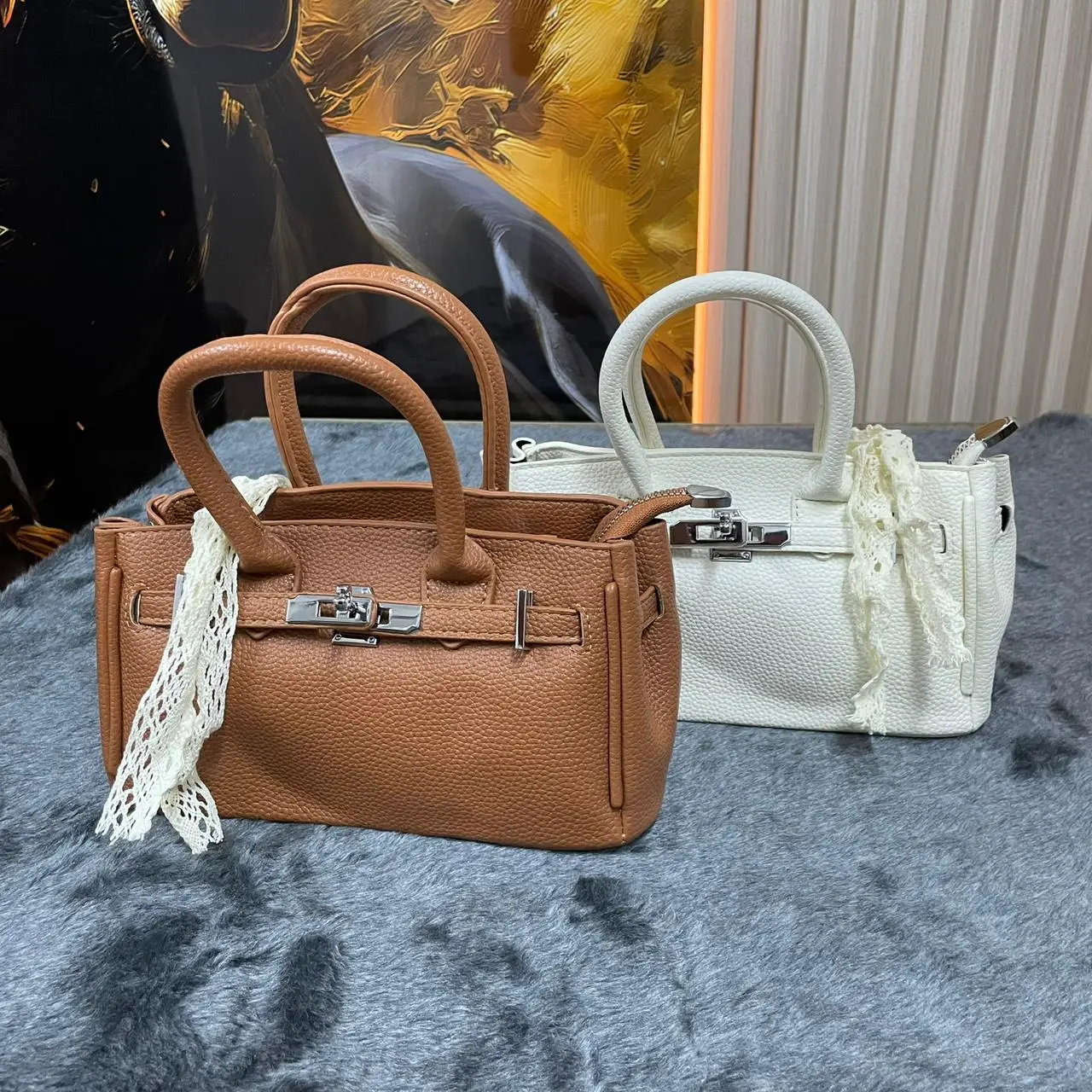 Bolso semi-rígido para dama con textura granulada en colores café y blanco, con asas cortas y detalle de encaje blanco.