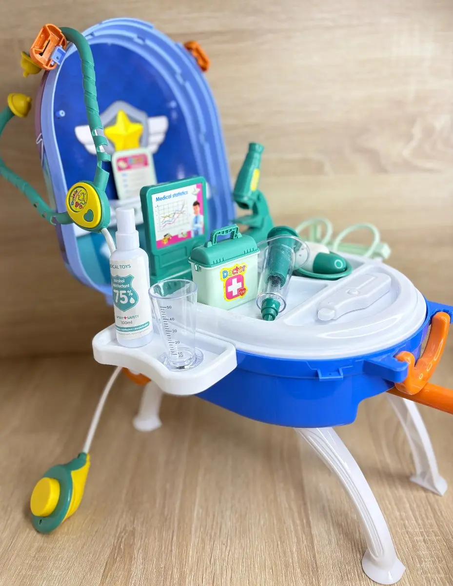 Set de doctor portátil azul con ruedas y accesorios médicos de juguete organizados sobre base desplegable con patas blancas.